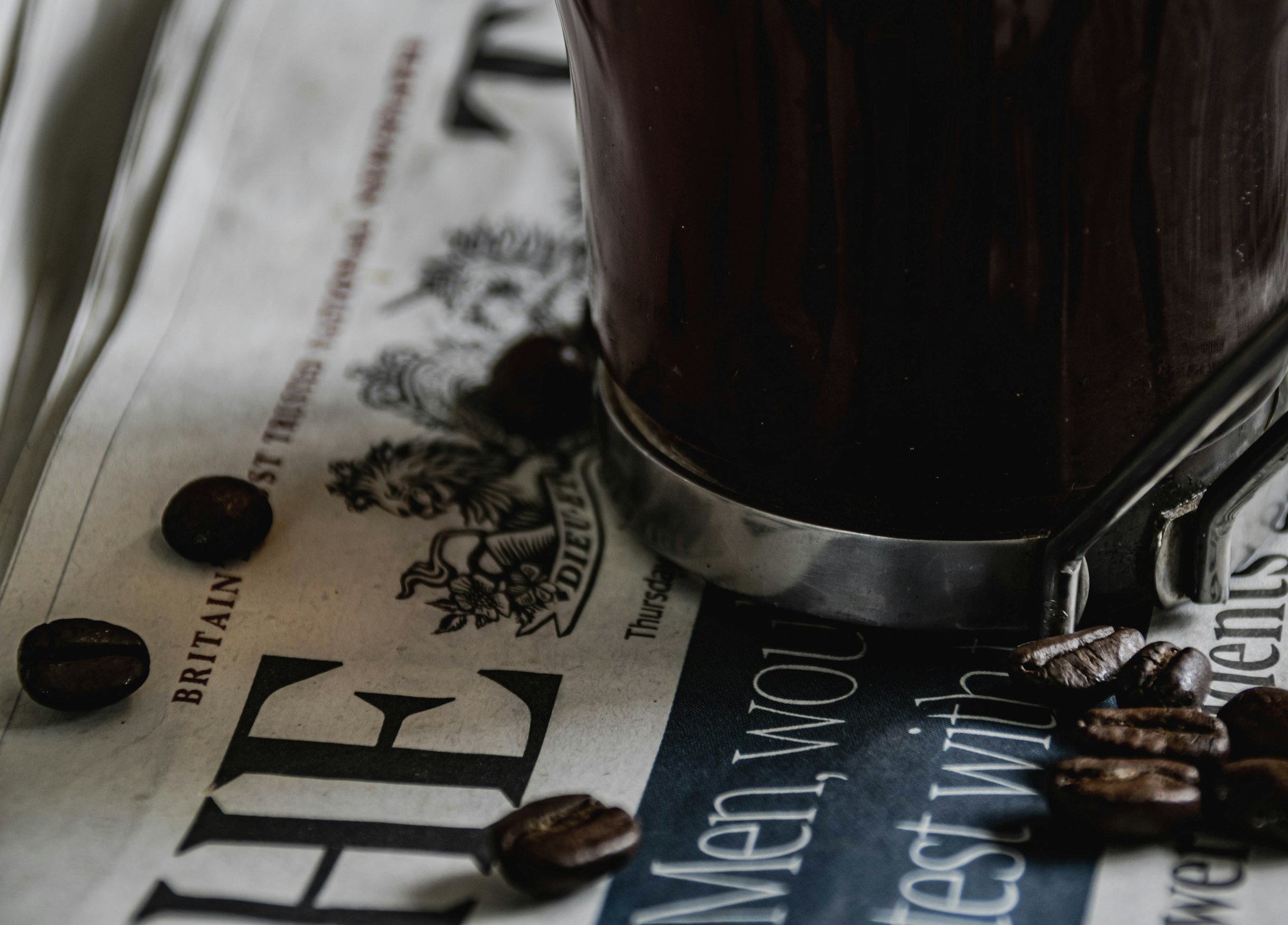 A cup of coffee sitting on top of a newspaper in the morning