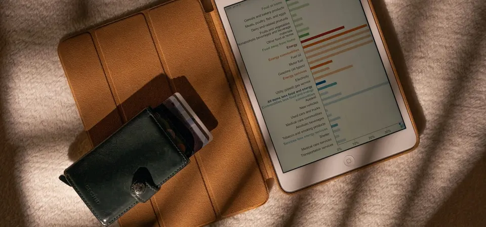 Tablet in a brown cover displaying a bar chart beside a wallet
