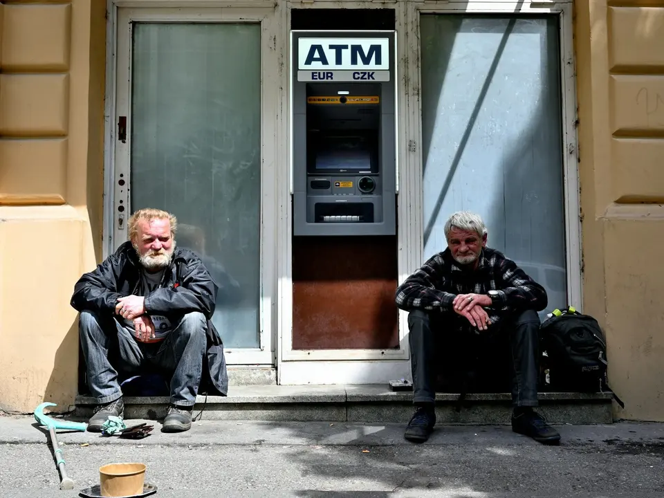Two people seated on steps on either side of an ATM
