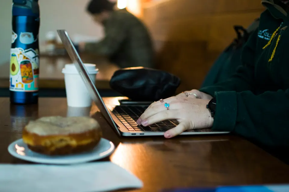 A person using a laptop at a wooden table