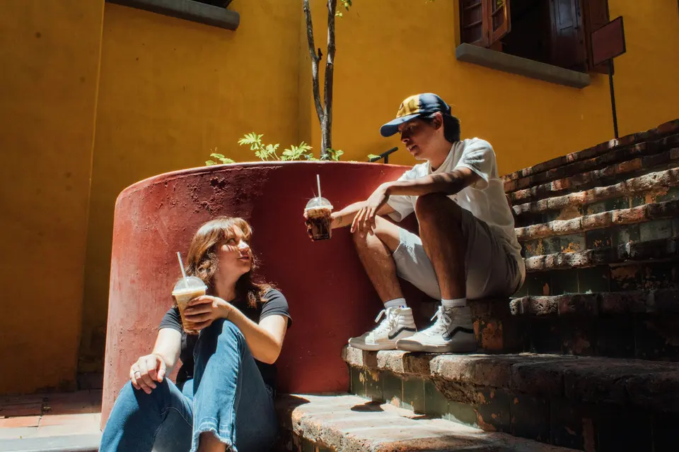 Two people sitting on outdoor steps with drinks