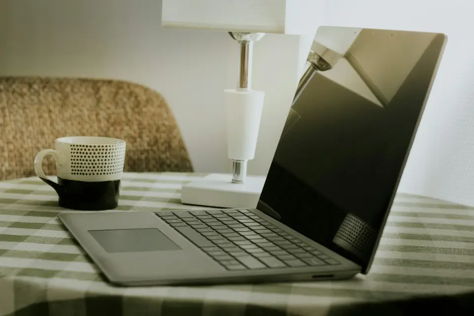 A laptop and coffee cup on a checkered tablecloth