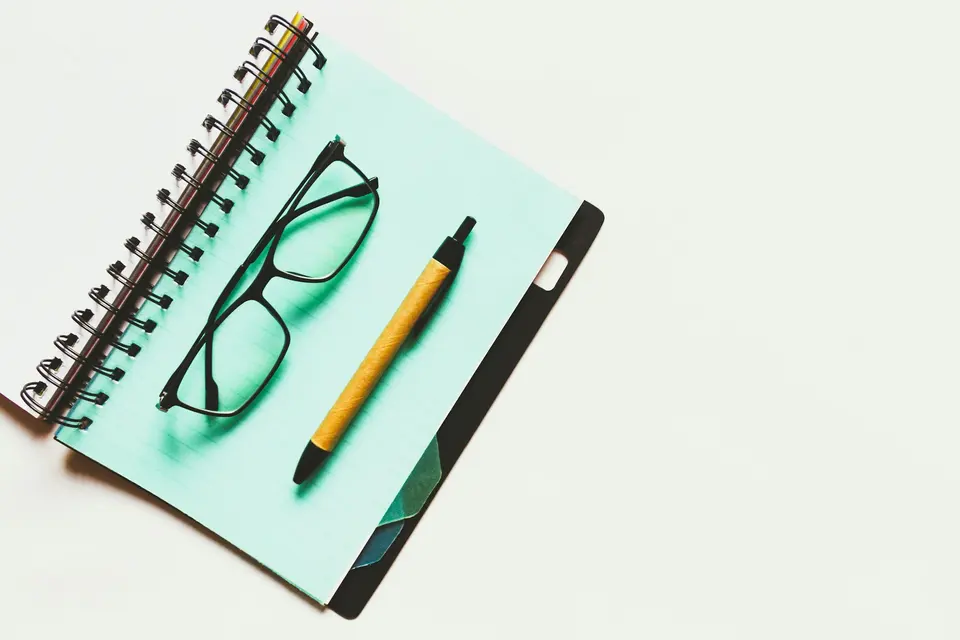 Black eyeglasses and brown click pen