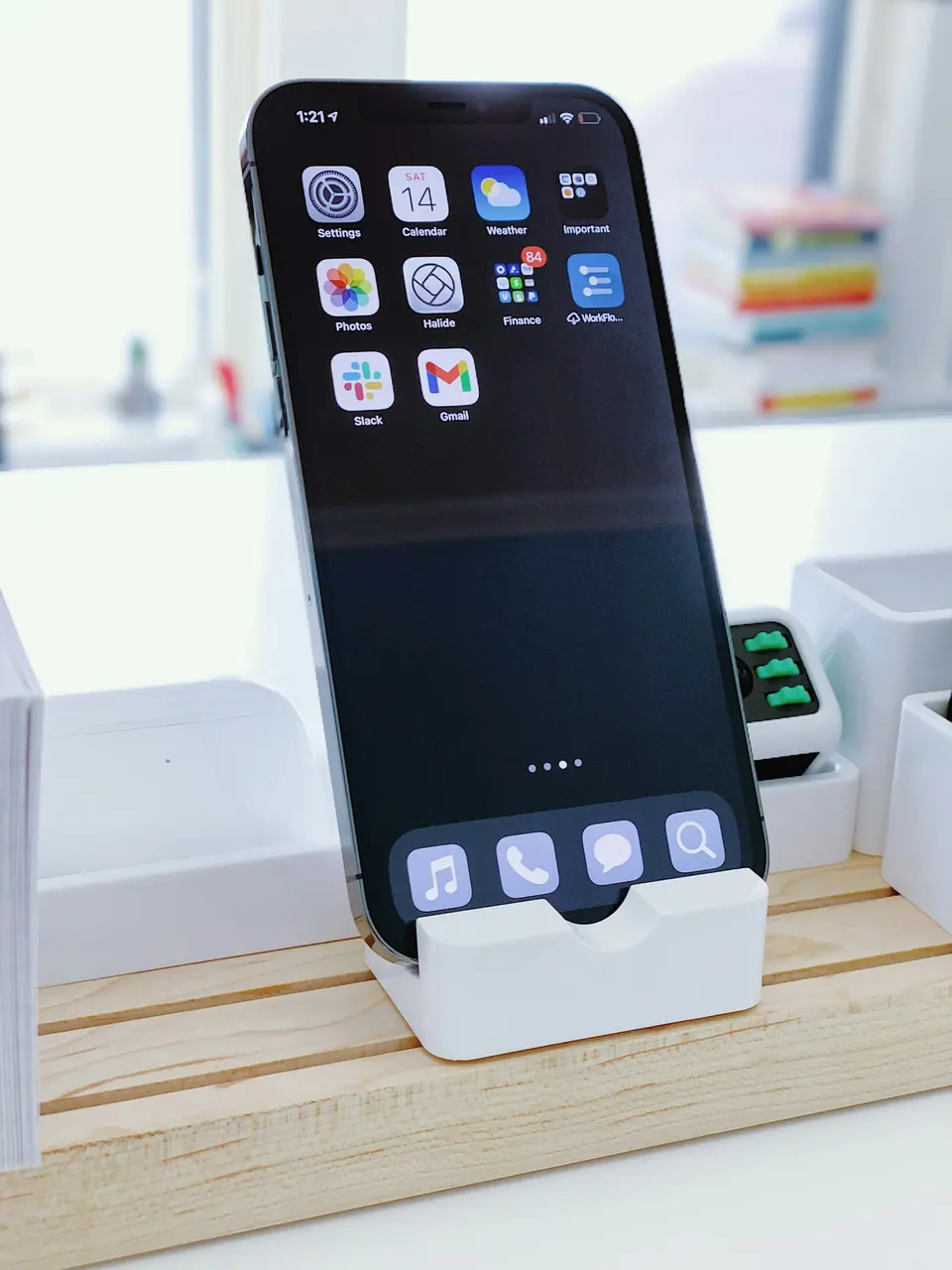 A smartphone displaying app icons on a white desk stand