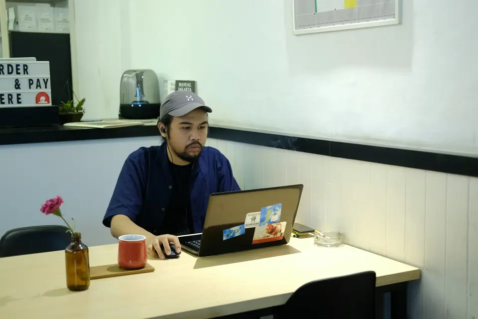 A person using a laptop at a cafe table with a red mug