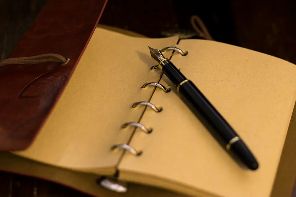 Open notebook with pen on a wooden desk in natural light