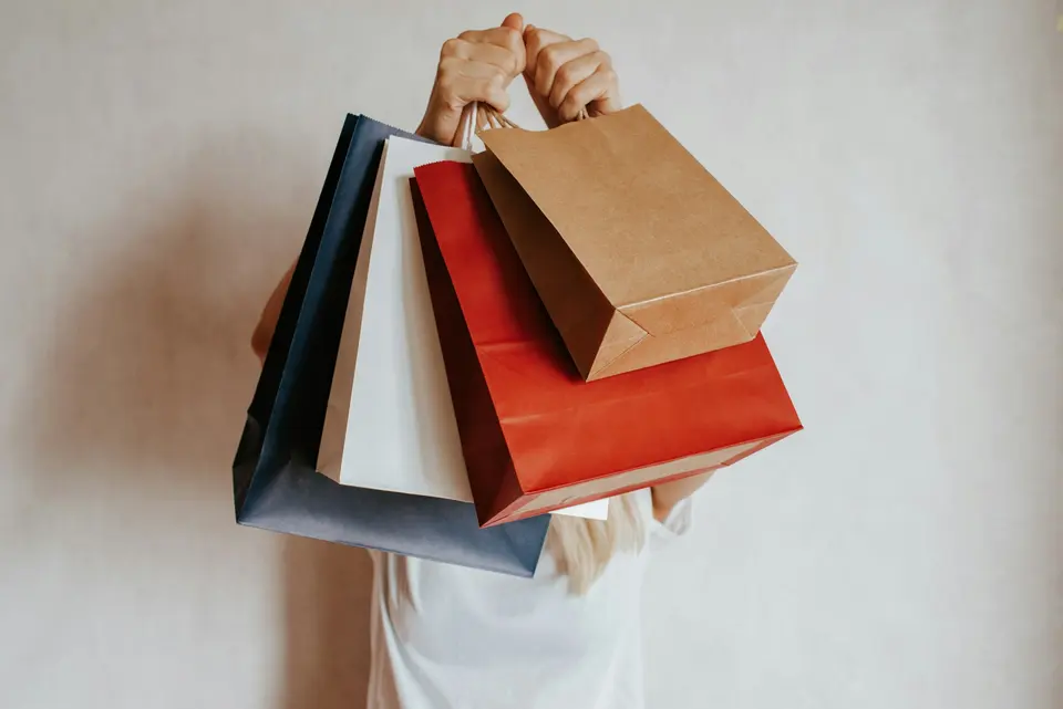 A person holding colorful shopping bags in front of their face