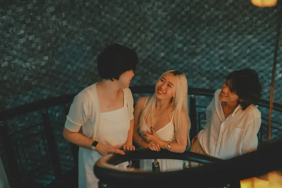 Three friends laughing together on a balcony