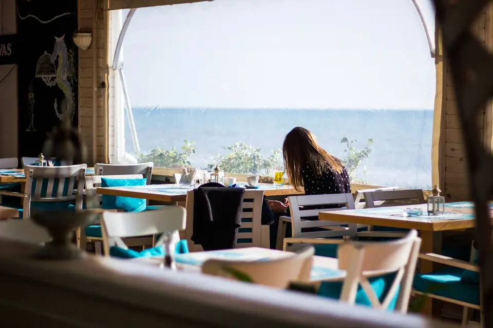 A woman sitting alone on a chair near a window