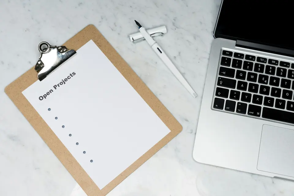 A printed checklist beside a laptop on a desk